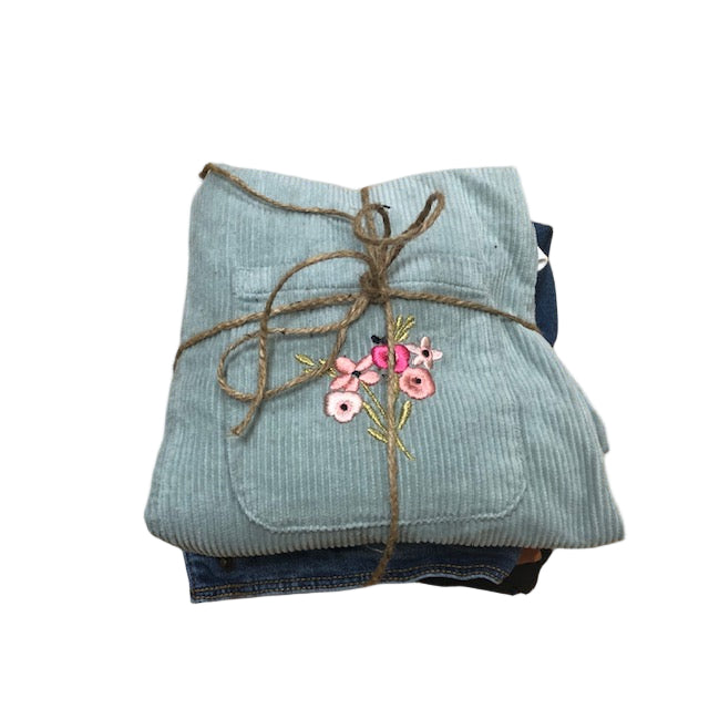 Folded blue garment with floral embroidery on a wooden surface