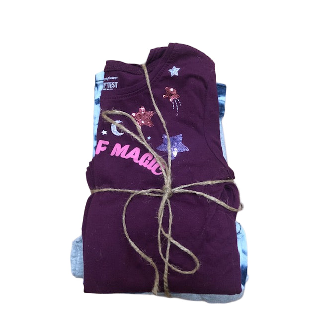 Folded purple shirt with text and graphics tied with twine on a wooden surface