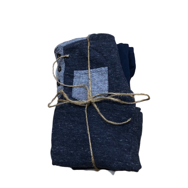 Folded dark blue fabric with a white square pattern, tied with twine on a wooden surface.